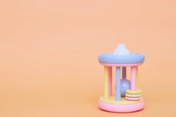 Juguete de pipa colorido de los niños sobre un fondo de melocotón. aislante de juguete para niños. Copiar espacio. el desarrollo de juguetes infantiles . — Foto de Stock