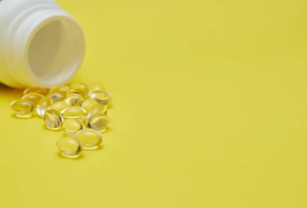 Cápsulas de medicina farmacêutica, comprimidos e cápsulas e um frasco sobre um fundo amarelo. Copiar espaço para texto. conceito de medecina e vitaminas em comprimidos . — Fotografia de Stock