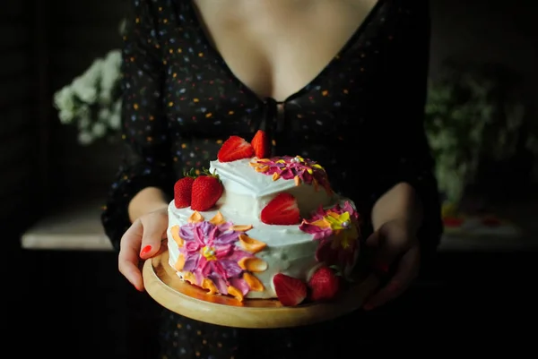 一个糖果在拿生日蛋糕 一个穿着连衣裙的女孩 手里拿着蛋糕在厨房里 一个厨师正在准备蛋糕 一个女孩手中的美丽蛋糕 图库图片