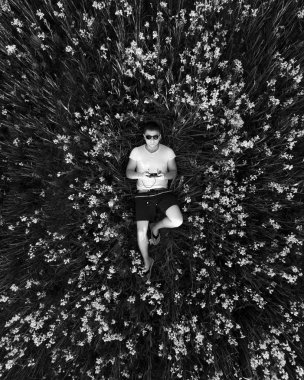 Genç bir adam bir dron çimlerin üzerinden günbatımında başlattı. Renk alanında. Yukarıdan görüntülemek.