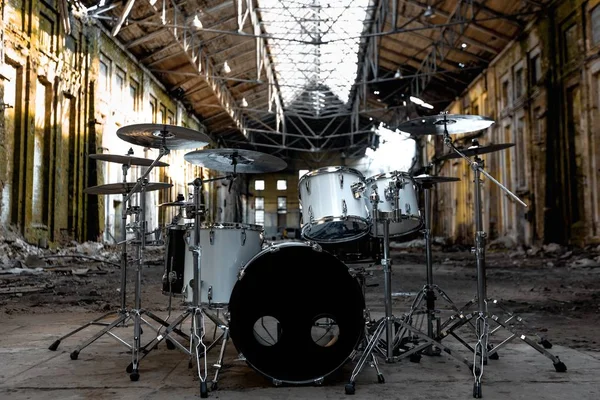 A white drum set stands in an abandoned hangar, an abandoned red brick plant. devastation, post apocalypse, urbex