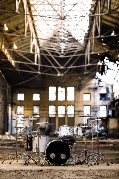 A white drum set stands in an abandoned hangar, an abandoned red brick plant. devastation, post apocalypse, urbex