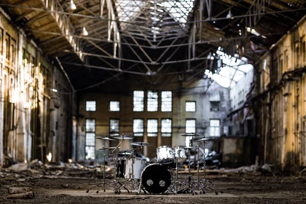 A white drum set stands in an abandoned hangar, an abandoned red brick plant. devastation, post apocalypse, urbex