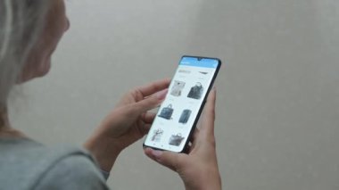 Mobil bir uygulama üzerinden alışveriş yapan genç bir kadın. İnternetten kadın çantası alıyor. İnternetten alışveriş. Kapatın. Mobil uygulama çevrimiçi mağazası.