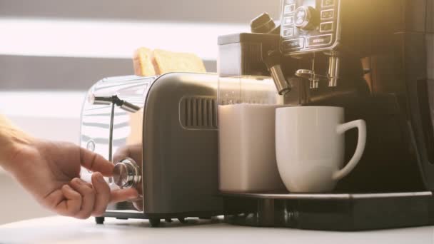 男はトーストと香り高いコーヒーを作る プロのコーヒーマシンでミルクとコーヒーを作るプロセス 朝食用トースト付きコーヒー — ストック動画