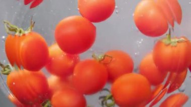 Taze kiraz domatesleri bir kase suya düşer. Taze sebze, domates. Domates yıkıyorum. Alttan kameraya bak. Yavaş çekim
