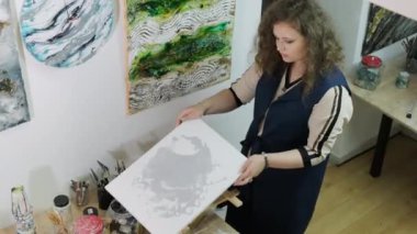 Genç ve yetenekli bir kadın sanatçı Akışkan Sanat tekniğini kullanarak bir resim çiziyor. Sıvı akrilik boyalarla resim çizmek.