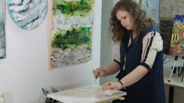 Genç ve yetenekli bir kadın sanatçı Akışkan Sanat tekniğini kullanarak bir resim çiziyor. Sıvı akrilik boyalarla resim çizmek.