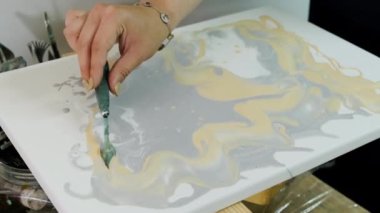 Sanatçı tuvale boya uygular. Sıvı akrilik boyalarla resim çizmek. Ressam, Sıvı Sanat tekniğini kullanarak bir resim çiziyor. Kapat.