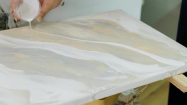 Sanatçı tuvale boya uygular. Sıvı akrilik boyalarla resim çizmek. Ressam, Sıvı Sanat tekniğini kullanarak bir resim çiziyor. Kapat.