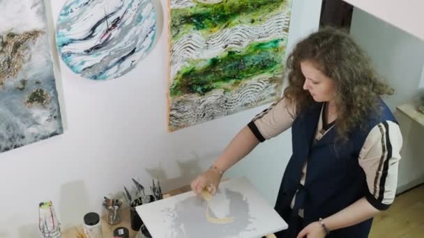 Mladá talentovaná umělkyně maluje obraz pomocí techniky Fluid Art. Kreslení obrazu kapalnými akrylovými barvami.