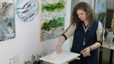 Genç ve yetenekli bir kadın sanatçı Akışkan Sanat tekniğini kullanarak bir resim çiziyor. Sıvı akrilik boyalarla resim çizmek.