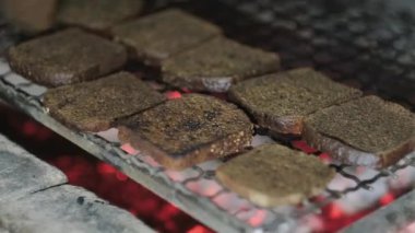 Şef, salata için kızarmış ekmek yapmak için ızgarada siyah ekmek dilimliyor.