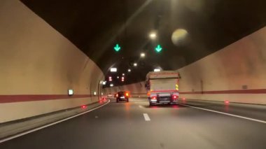 Bir araba uzun bir tünelden geçiyor. Yol dağlık bir bölgedeki bir tünelden geçiyor. Bir dağın içinden tünel