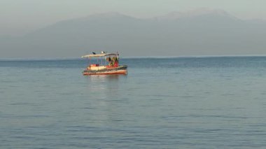 Balıkçı teknesi Ege Körfezi 'ndeki dalgalarda sallanıyor. Yazın şafak vakti sakin deniz. Yunanistan 'da deniz, Halkidiki. Rahatlatıcı, rahatlatıcı video