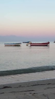 Ege Körfezi 'ndeki dalgalarda sallanan balıkçı tekneleri. Yazın şafak vakti sakin deniz. Yunanistan 'da deniz, Halkidiki. Rahatlatıcı, rahatlatıcı yavaş çekim videosu