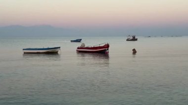 Ege Körfezi 'ndeki dalgalarda sallanan balıkçı tekneleri. Yazın şafak vakti sakin deniz. Yunanistan 'da deniz, Halkidiki. Rahatlatıcı, rahatlatıcı yavaş çekim videosu
