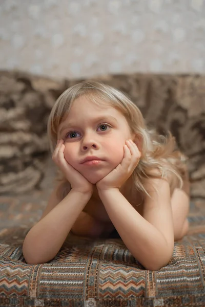 4 roky starý chlapec leží na gauči a dívá se na televizi. portrét plavovlasého chlapce. — Stock fotografie