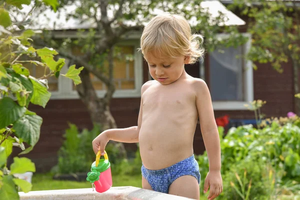 Niño pequeño con regadera de juguete, agua vertida. día de verano . —  Fotos de Stock