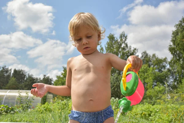 Niño pequeño con regadera de juguete, agua vertida. día de verano . —  Fotos de Stock