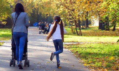 Park ve anne ve güneşli bir sonbaharda üstünde o kızı yolda çok biraz hüzünlü yaprakları