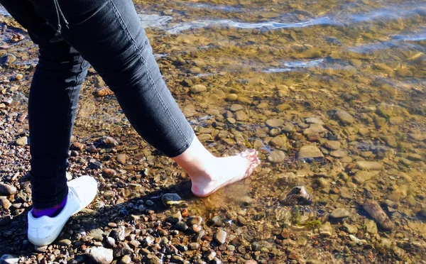 秋の冷たい水の中の少女の脚 太陽が輝いています — ストック写真