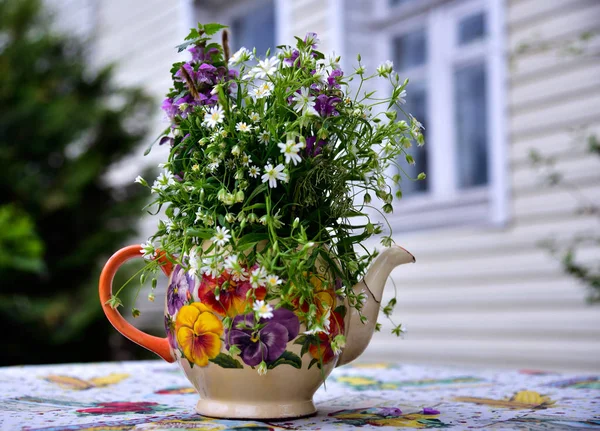 Vase of flowers stands in the garden near the country house summer