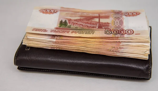Beş bin banknottan oluşan bir paket kahverengi bir çantanın üzerinde, gri bir arka plan da yatıyor..