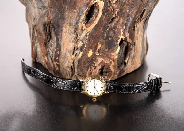 Reloj de pulsera con esfera de oro y correa de cuero negro sobre fondo de madera . — Foto de Stock