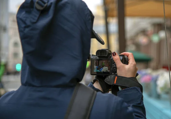 Lány-fotós veszi fotók veranda szabadtéri kávézó a város utcáin. A fotót a hátsó, a kamera képernyőjén látható egy előnézet — Stock Fotó