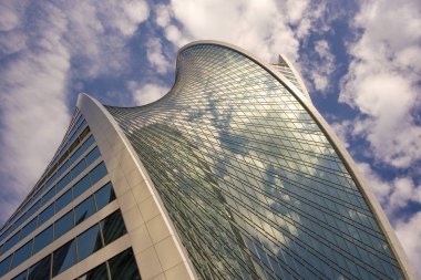 Mavi gökyüzüne ve uçan bulutlara karşı gökdelen parçaları. Mimari üslup - modernizm.