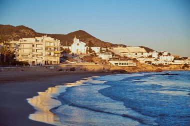 Sahilde küçük bir kasaba, batan güneşin ışınları ile aydınlatılmış.