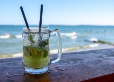 İki siyah tüpler ile barda bir buharda Mojito bardak. Deniz ve mavi gökyüzüne karşı.