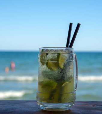 İki siyah tüpler ile barda bir buharda Mojito bardak. Deniz ve mavi gökyüzüne karşı.