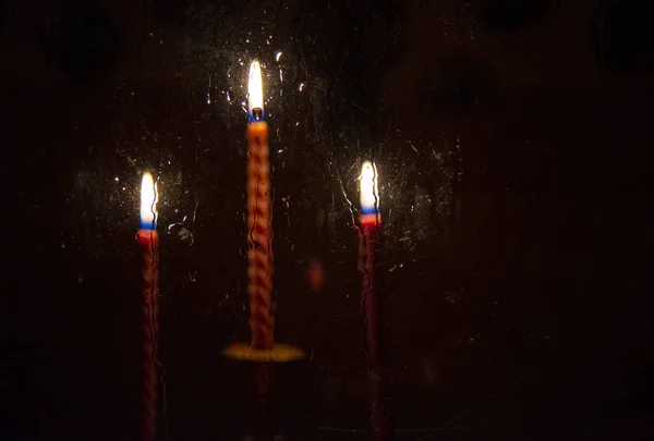 Three red burning candles photographed through glass. — Stock Photo, Image