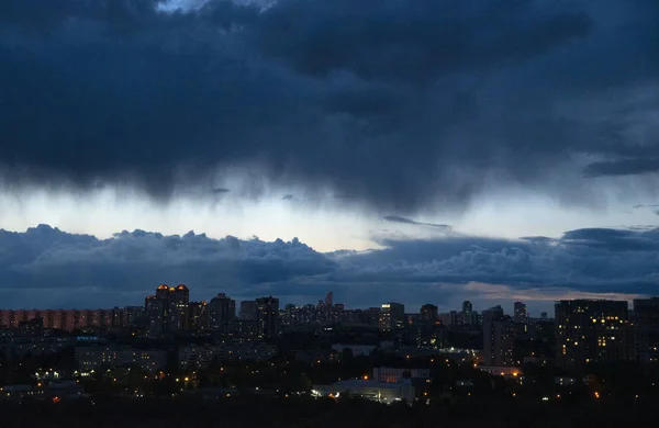 Fondo. Oscuras nubes irregulares sobre la ciudad nocturna . — Foto de Stock