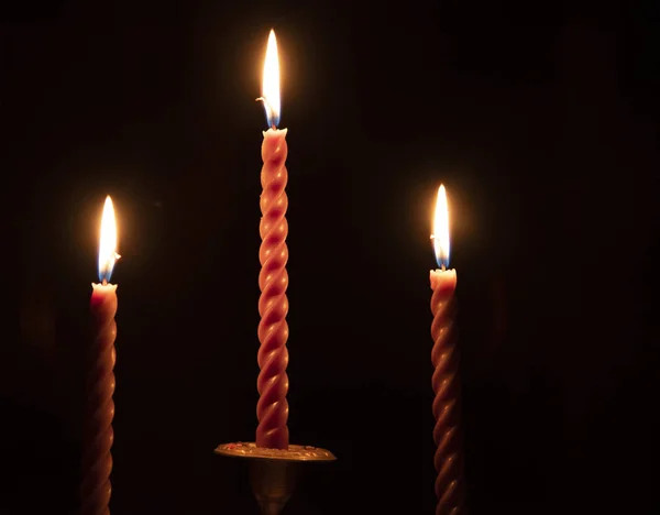 Trois bougies rouges torsadées sur fond sombre . — Photo