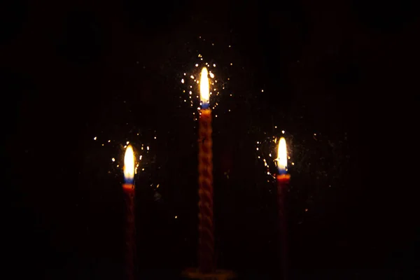Rozostřené tři červené zkroucené svíčky za sklem. Oheň se odráží v kapiček vody — Stock fotografie