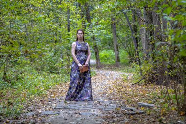 Orta yaşlı bir kadın sonbahar Parkı'nda yolda duruyor..