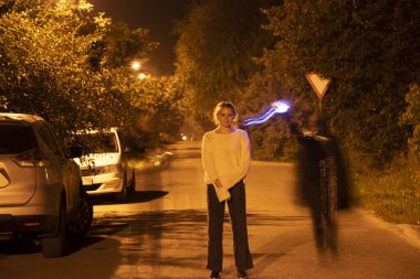Uzun pozlama gece çekilen fotoğraf. Hayalete benzeyen bir adamın üzerinde duran bir köy yolu..