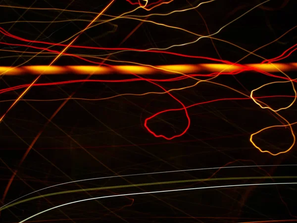 Líneas de luz abstractas sobre un fondo oscuro, que se cruzan en diferentes lugares . — Foto de Stock