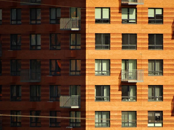 Hoek van een huis met ramen en balkons. De ene kant wordt verlicht door de zon — Stockfoto