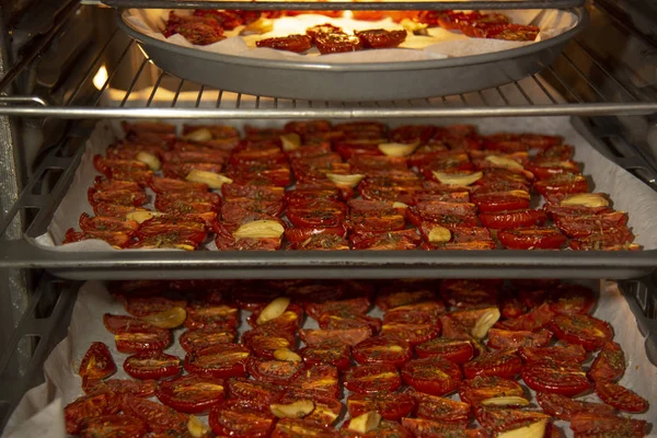 Le processus de cuisson des tomates séchées.Légumes avec des épices au four sur des plateaux sur trois niveaux . — Photo