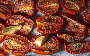 Taze pişmiş güneşte kurutulmuş domates, baharat serpilir parşömen üzerine serilir. Aralarında karanfil sarımsak.