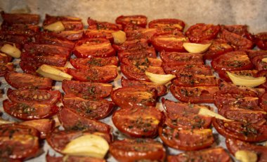 Taze pişmiş güneşte kurutulmuş domates, baharat serpilir parşömen üzerine serilir. Aralarında karanfil sarımsak.