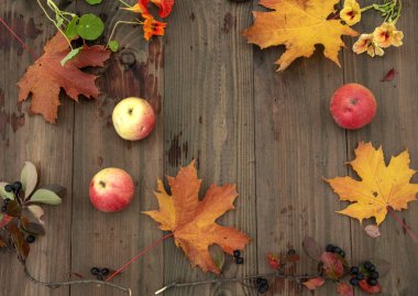 Elma, çilek, sonbahar yaprakları ve ahşap bir arka plan üzerinde çiçekler.
