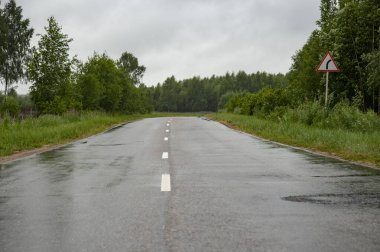 Yol yağmurla ıslanmış, uzaklara doğru uzanıyor.