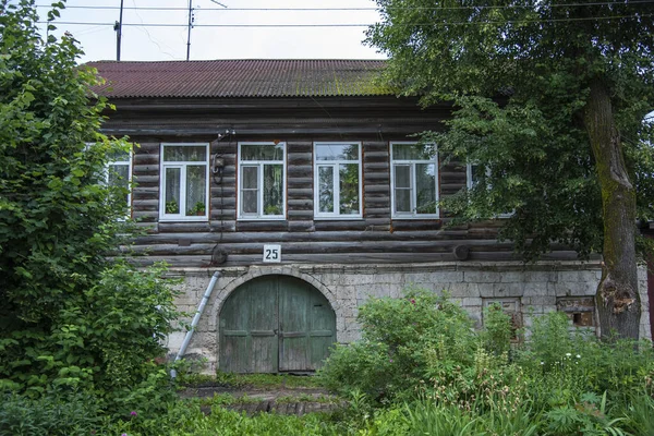 Uma velha casa de madeira com uma linha de janelas e um portão . — Fotografia de Stock