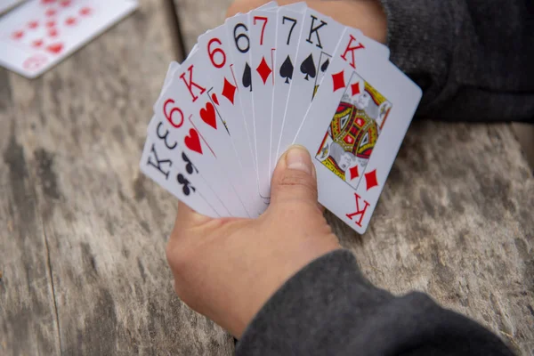 Playing cards in human hands on a wooden background.