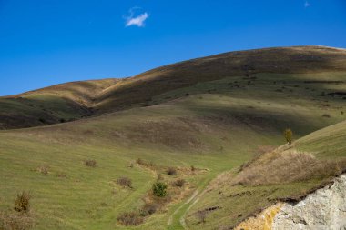 Mavi gökyüzüne karşı yeşil tepelerdeki patika.